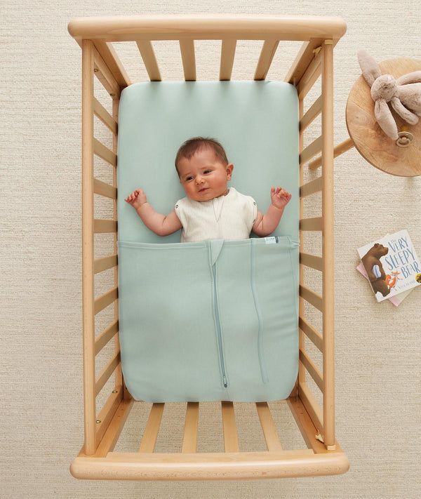 Baby wearing a lightweight ergoPouch Cocoon Swaddle Bag 0.2 TOG Oatmeal Marle