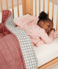 Toddler lying in bed on an ergoPouch low-profile pillow, made from premium, skin-friendly materials.