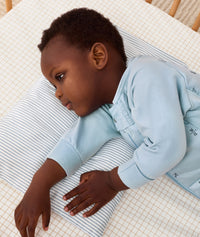 Toddler lying in bed on an ergoPouch low-profile pillow, featuring stripe protector design.