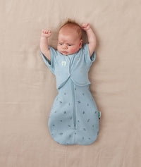 Newborn baby wearing a blue ergoPouch swaddle with a matching butterfly cardi.