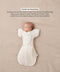 Sleeping baby lying on their back in a Cocoon Swaddle Bag with a matching Butterfly Cardi, enabling hands-up swaddled sleeping.