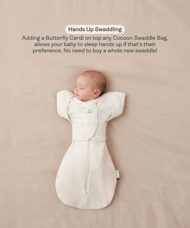 Sleeping baby lying on their back in a Cocoon Swaddle Bag with a matching Butterfly Cardi, enabling hands-up swaddled sleeping.