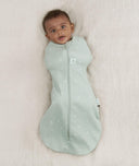 Newborn wearing an ergoPouch Cocoon Swaddle Bag 0.2 TOG Sage with arms in