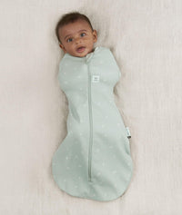 Newborn wearing an ergoPouch Cocoon Swaddle Bag 0.2 TOG Sage with arms in