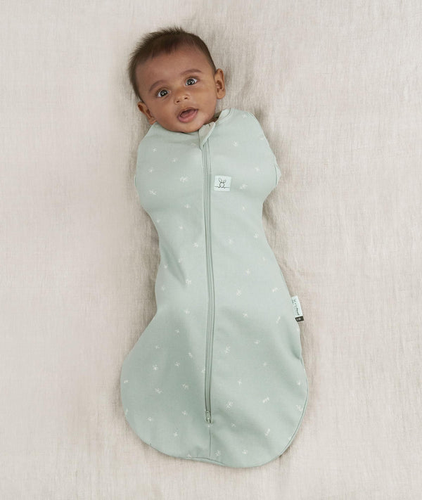 Newborn wearing an ergoPouch Cocoon Swaddle Bag 0.2 TOG Sage with arms in