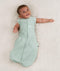 Newborn wearing an ergoPouch Cocoon Swaddle Bag 0.2 TOG Sage with arms out