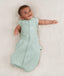 Newborn wearing an ergoPouch Cocoon Swaddle Bag 0.2 TOG Sage with arms out