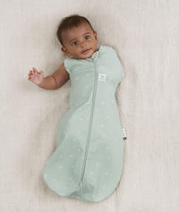 Newborn wearing an ergoPouch Cocoon Swaddle Bag 0.2 TOG Sage with one arm out