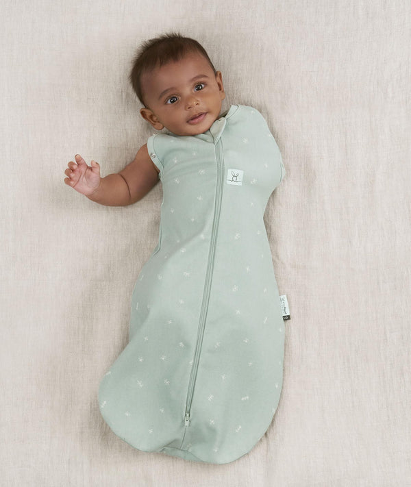 Newborn wearing an ergoPouch Cocoon Swaddle Bag 0.2 TOG Sage with one arm out