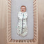 Baby lying in a cot wearing a Cocoon Swaddle Bag 2.5 TOG Clouds