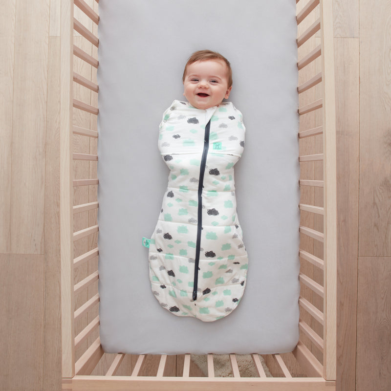 Baby lying in a cot wearing a Cocoon Swaddle Bag 2.5 TOG Clouds
