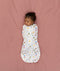 Newborn lying on a bed sleeping in a ergoPouch Cocoon Swaddle Bag 1.0 TOG Daydream