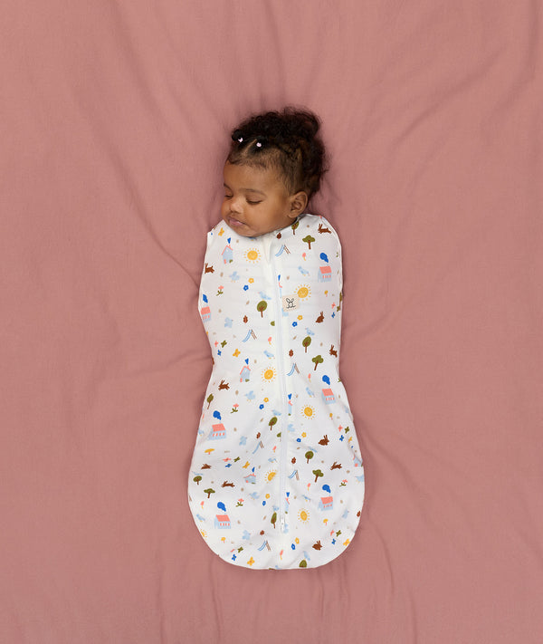 Newborn lying on a bed sleeping in a ergoPouch Cocoon Swaddle Bag 1.0 TOG Daydream