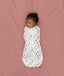 Newborn lying on a bed sleeping in a ergoPouch Cocoon Swaddle Bag 1.0 TOG Daydream