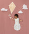 Newborn asleep in ergoPouch Cocoon Swaddle Bag 0.2 TOG Daydream, arms out sleeping, with a geometric kite and clouds