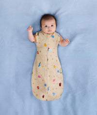 Newborn wearing an ergoPouch Cocoon Swaddle Bag 1.0 TOG Birthday Blobs with arms out
