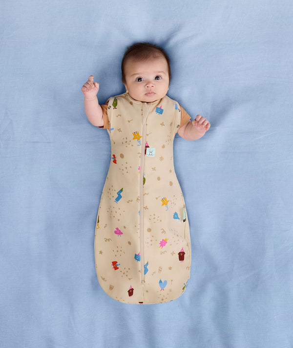 Newborn wearing an ergoPouch Cocoon Swaddle Bag 1.0 TOG Birthday Blobs with arms out
