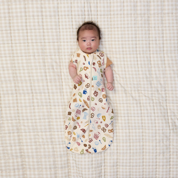 Baby with two arms out of ergoPouch Cocoon Swaddle Bag 1.0 TOG in Bon Appetit