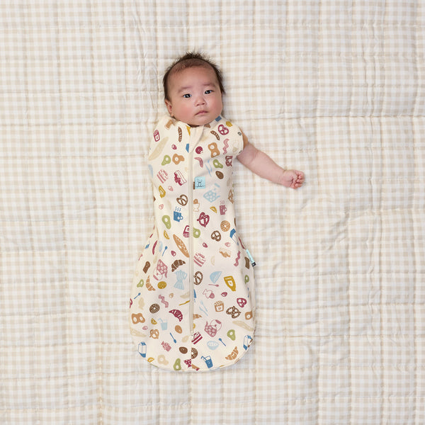 Baby transitioning to arms out sleeping with one arm out of ergoPouch Cocoon Swaddle Bag 1.0 TOG in Bon Appetit