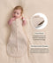 Baby lying in a beige patterned Cocoon Swaddle Bag, with callouts highlighting armhole press studs and a stretchy bell-shaped bottom design.