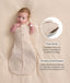 Baby lying in a beige patterned Cocoon Swaddle Bag, with callouts highlighting armhole press studs and a stretchy bell-shaped bottom design.
