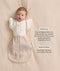 Baby wearing a beige Cocoon Swaddle Bag layered with a cream 