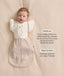 Baby wearing a beige Cocoon Swaddle Bag layered with a cream 