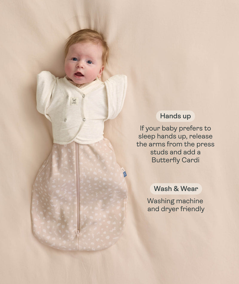 Baby wearing a beige Cocoon Swaddle Bag layered with a cream 