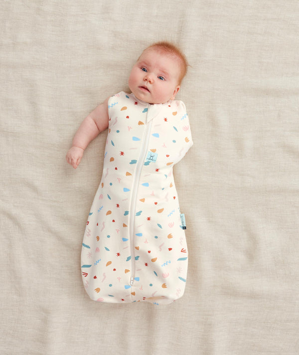 Baby wearing a Cocoon Swaddle Bag 1.0 TOG Desert Bloom, one arm out