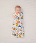 Newborn wearing an ergoPouch Cocoon Swaddle Bag 1.0 TOG Fruit Salad with one arm out