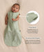 Baby lying on a cream blanket, wearing an ergoPouch Cocoon Swaddle Bag 1.0 TOG with text callouts highlighting press studs and stretchy & bell-shaped design.