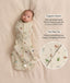 A baby lying on a light background wearing an animal-patterned Cocoon Swaddle Bag with product feature callouts: organic cotton and two-way zip. A circular inset zooms in on the double-zipper detail.