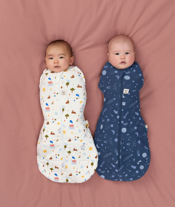 Two babies swaddled in ergoPouch Cocoon Swaddle Bag Daydream and Starbeam, to mimic the wound