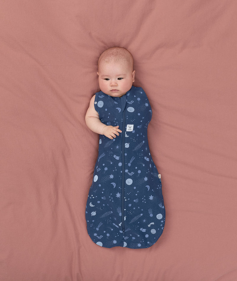 Baby transitioning to arms out sleeping easily with the ergoPouch Cocoon Swaddle Bag 1.0 TOG Starbeam
