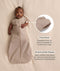 Baby lying on a cream blanket, wearing an ergoPouch 1.0 TOG Cocoon Swaddle Bag with both arms out. On the right, two feature callouts highlighting 