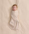 An overhead view of a baby swaddled in a patterned beige Cocoon Swaddle Bag, lying flat on a cream-colored blanket.
