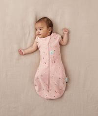 Baby wearing a lightweight ergoPouch Cocoon Swaddle Bag 0.2 TOG Daisies with arms out