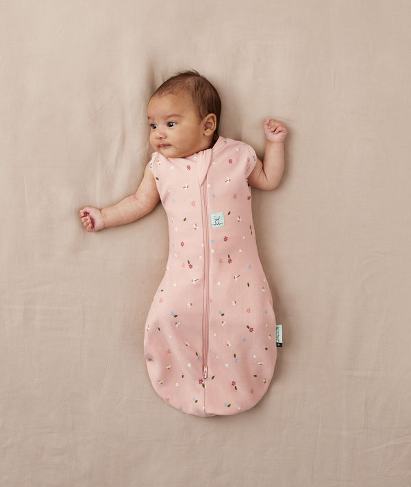 Baby wearing a lightweight ergoPouch Cocoon Swaddle Bag 0.2 TOG Daisies with arms out