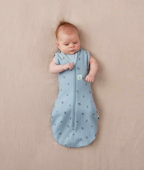 Newborn wearing an ergoPouch Cocoon Swaddle Bag 1.0 TOG Dragonflies with arms out