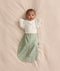 Baby wearing a sage green floral Cocoon Swaddle Bag layered with a white 