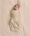 Baby lying on a cream blanket swaddled in a safari-patterned Cocoon Swaddle Bag 1.0 TOG.