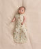 Baby lying on a cream-colored blanket wearing a Cocoon Swaddle Bag 1.0 TOG with both arms out.