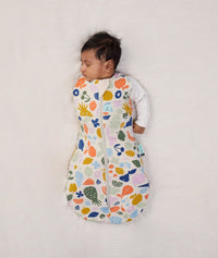 Newborn wearing an ergoPouch Cocoon Swaddle Bag 2.5 TOG Fruit Salad with one arm out