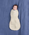 Baby lying on a blue fabric background, wrapped in a cream patterned Cocoon Swaddle Bag 2.5 TOG