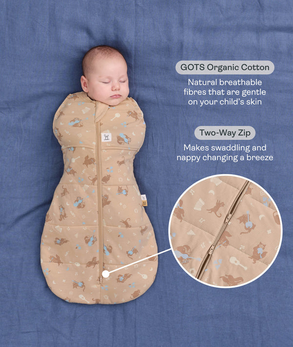 Product graphic featuring a sleeping baby in a tan Cocoon Swaddle Bag, highlighting Organic Cotton and a Two-Way Zip feature with a close-up inset.