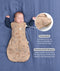 Product infographic showing a baby sleeping arms-out in a Cocoon Swaddle Bag on a blue background, highlighting armhole press studs and a bell-shaped design.
