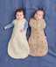 Two babies lying side by side wearing ergoPouch Cocoon Swaddle Bag in Lullaby and Melody.