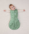 Newborn wearing an ergoPouch Cocoon Swaddle Bag 2.5 TOG Sweet Orchard with arms out