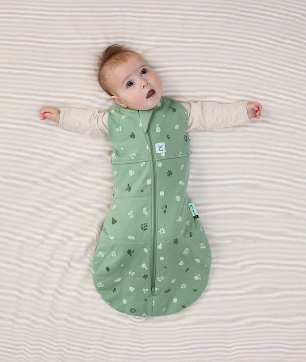Newborn wearing an ergoPouch Cocoon Swaddle Bag 2.5 TOG Sweet Orchard with arms out