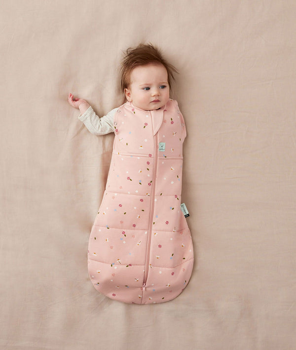Newborn wearing an ergoPouch Cocoon Swaddle Bag 2.5 TOG Daisies with one arm out